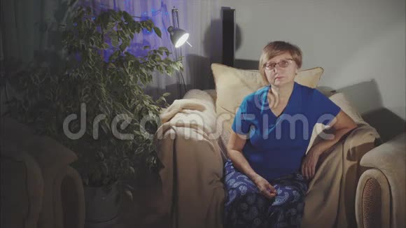 幸福的老妇人坐在家里的扶手椅上的画像视频的预览图