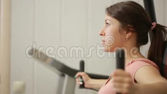 漂亮的女孩在健身房训练从事运动模拟器的女性视频的预览图