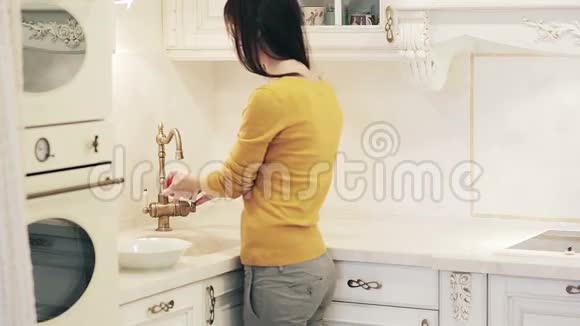 美丽的女孩在厨房里洗苹果视频的预览图