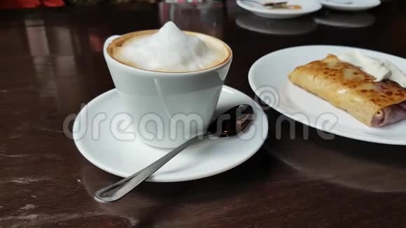 咖啡桌上有卡布奇诺和煎饼和酸奶油视频的预览图