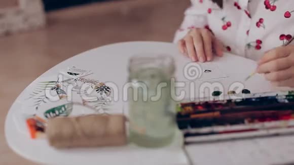 女孩用画笔和水彩画在纸上手工制作的节日装饰品视频的预览图