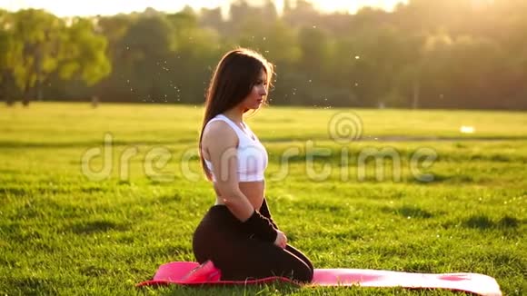 年轻漂亮的女人正在休息时坐在垫子上健身运动后在阳光下休息视频的预览图