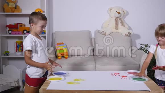 一个小可爱快乐有趣的孩子在白纸上画彩色手印视频的预览图