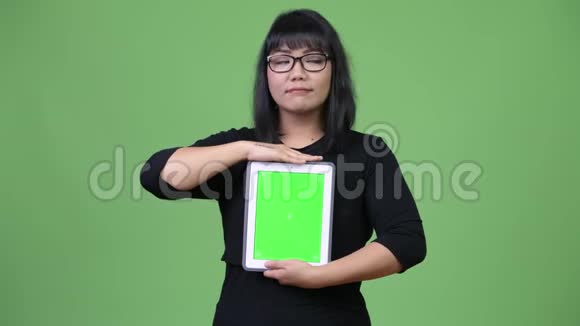 美丽的亚洲女商人展示数字平板电脑和思考视频的预览图