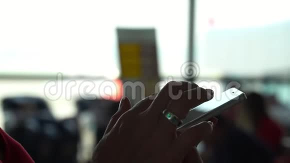 在机场窗口用信使或智能手机输入短信的女性手的特写镜头登机飞机视频的预览图