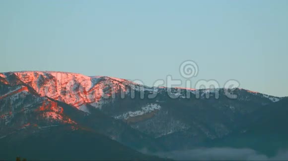 雪中的群山在黎明时被太阳照亮视频的预览图