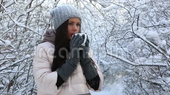 美丽的快乐女孩用热茶温暖起来雪视频的预览图