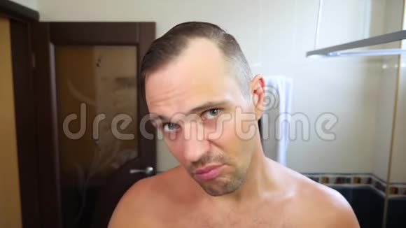 年轻有魅力的男人在浴室里检查一条后退的发际线秃头4k慢动作视频的预览图