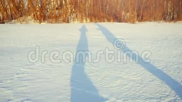 浪漫的情侣在冬天阳光明媚的白天慢动作在雪地上徒步旅行的影子1920x1080视频的预览图