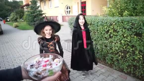 两个孩子男孩和女孩穿着黑色的万圣节服装拿糖果视频的预览图