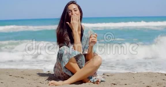 坐在沙滩上亲吻她的手掌视频的预览图