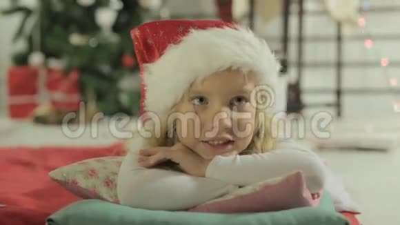 戴着圣诞老人帽子的迷人小女孩躺在视频的预览图