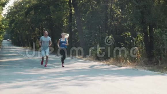 一对夫妇沿着一条森林道路奔跑视频的预览图