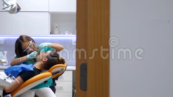 一位年轻的女牙医在牙医办公室里进行了一次移动的拍摄她正在检查和研究病人的牙齿视频的预览图