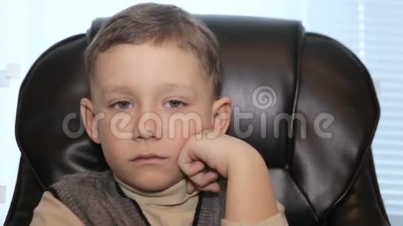 严肃的男孩坐在扶手椅上特写镜头视频的预览图