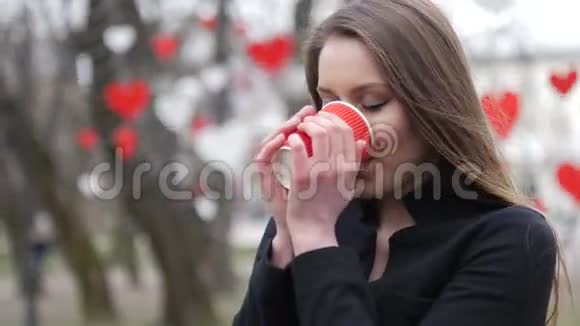秋天公园背景下年轻美丽的金发女郎和喝杯外卖的画像视频的预览图