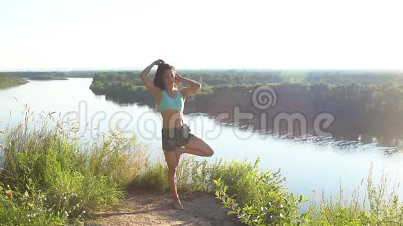 美丽的年轻女性在户外练习瑜伽动作和姿势在一个令人难以置信的悬崖上视频的预览图