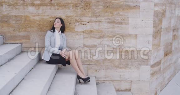 严肃的女人坐在户外的楼梯上视频的预览图