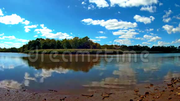 平静的一天在湖边天空树和云在湖水上倒影视频的预览图