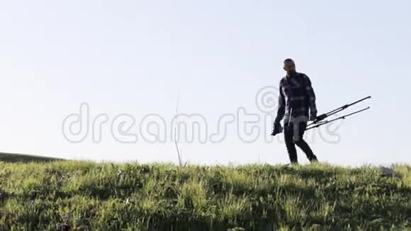 野生动物自然摄影师与三脚架步行在山景视频的预览图