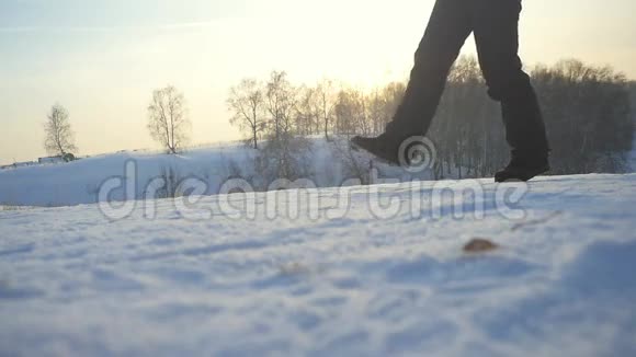女旅行者在冬天寒冷的雪天跋涉女孩的腿在自然的五彩缤纷的日落天空中缓慢地行走视频的预览图