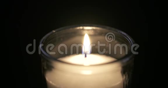 一支蜡烛在黑暗的背景上发出的宏光视频的预览图