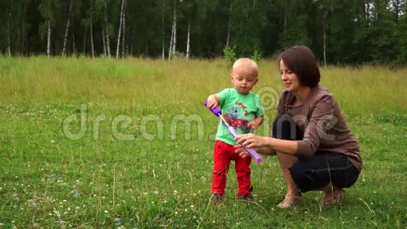 可爱的年轻妈妈带着一个小儿子跑肥皂泡视频的预览图
