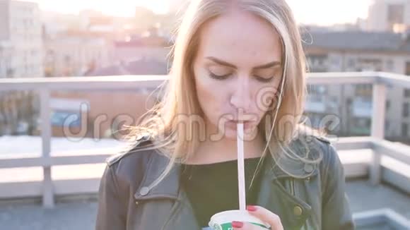 小女孩在日落时用吸管喝果汁手里拿着球视频的预览图