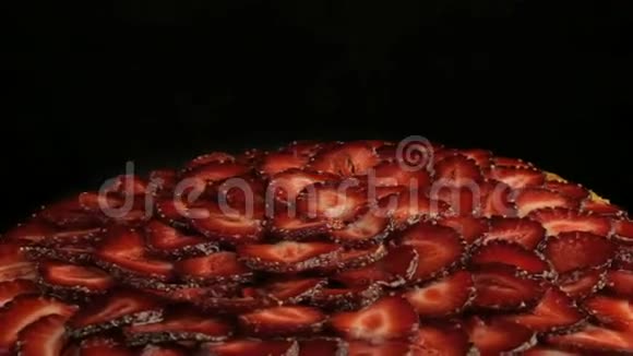 蛋糕上有很多美味的红色草莓在黑色的背景上逆时针旋转视频的预览图