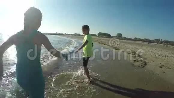 女孩和男孩沿着冲浪线在水中奔跑视频的预览图