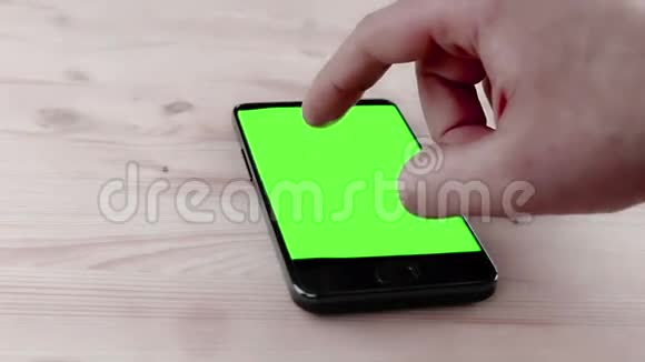 在办公室使用带有色度键的智能手机在木桌上使用绿色屏幕视频的预览图