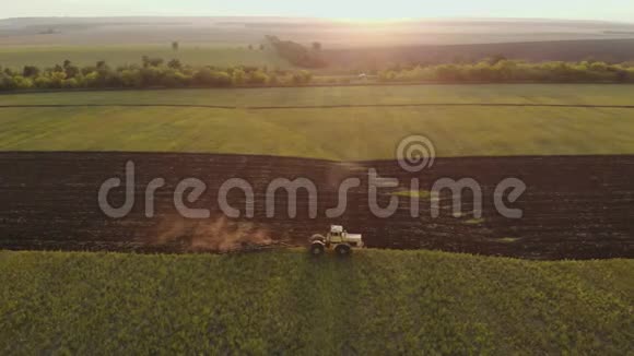 日落时分在农田上鸟瞰现代红色拖拉机拖拉机耕地和耕地视频的预览图