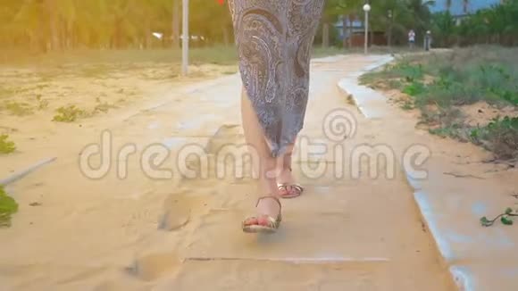 年轻女孩的腿沿着混凝土路穿过一个热带公园近距离射击视频的预览图