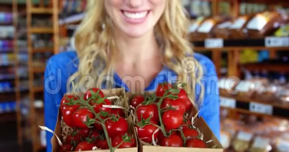超市里拿着一盒樱桃番茄的女员工微笑视频的预览图