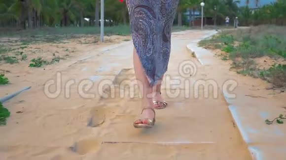 年轻女孩的腿沿着混凝土路穿过一个热带公园近距离射击视频的预览图