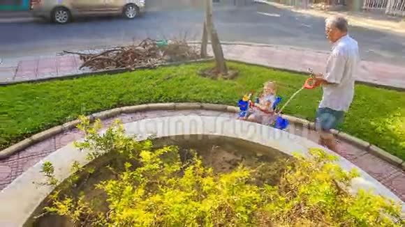 爷爷在公园里用小女孩的智能手机冲三轮车视频的预览图