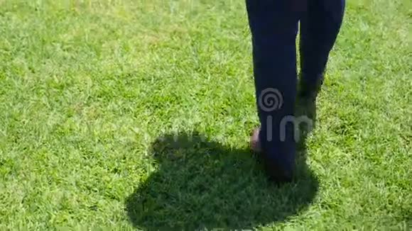 穿着时尚复古鞋的新郎走在绿草草坪上背面视频的预览图