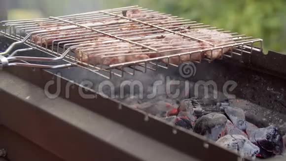 男人在烧烤上煮肉那个人把肉烧在格子上肉在火上煎烧烤烧烤视频的预览图