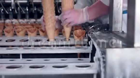特写镜头的移动皮带与冰淇淋锥和一个工人采取他们食品工业视频的预览图