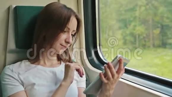 坐在火车上拿着平板电脑的年轻女子视频的预览图