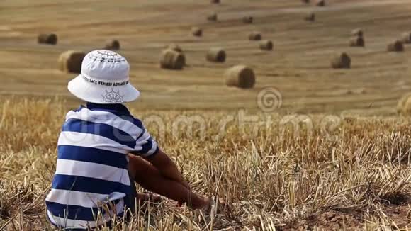 一个男孩坐在农场的田野里有很多干草堆背景视频的预览图