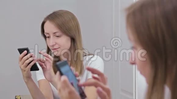 坐在镜子前用智能手机的女人视频的预览图