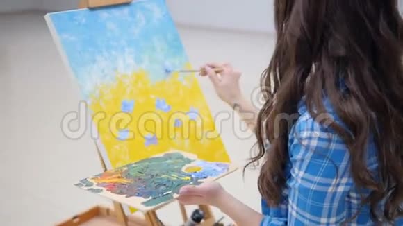 女孩在画布上画蓝色的花视频的预览图