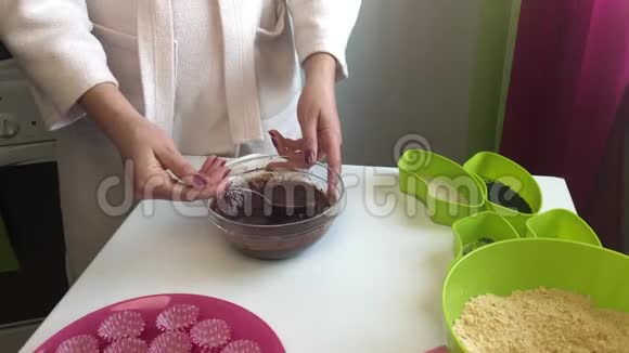 一名妇女将可可粉和融化的黄油混合倒入一个装有碎饼干的容器中为了做糖果视频的预览图