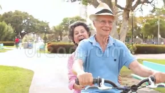 在公园骑自行车的资深西班牙夫妇视频的预览图