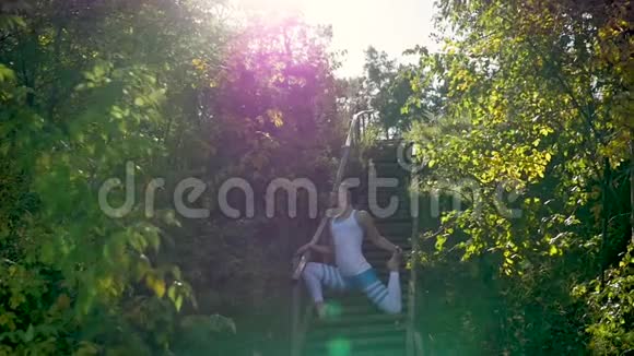 女人在楼梯上的公园里做瑜伽太阳射线视频的预览图