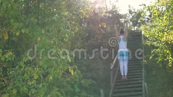 女人在楼梯上的公园里做瑜伽太阳射线视频的预览图