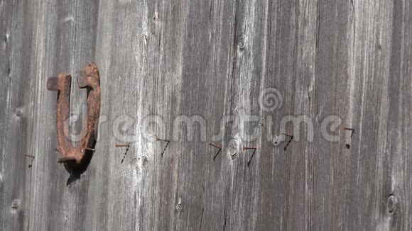 乡下女人的手把生锈的旧马蹄挂在古老的木门上象征着幸运4K视频的预览图