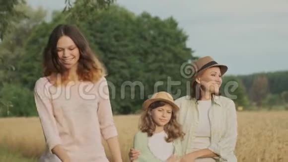 家庭母亲和孩子两个女儿一起走在乡间小路上夏天的自然背景视频的预览图
