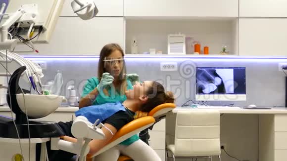 一位年轻的女牙医在一家牙医办公室里拍摄了一张移动的照片她正在检查病人的牙齿视频的预览图